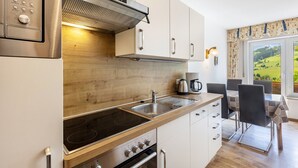 Eine moderne Küche mit Einbauherd, einer Kaffeemaschine und einem Essbereich mit Tisch und Stühlen.
