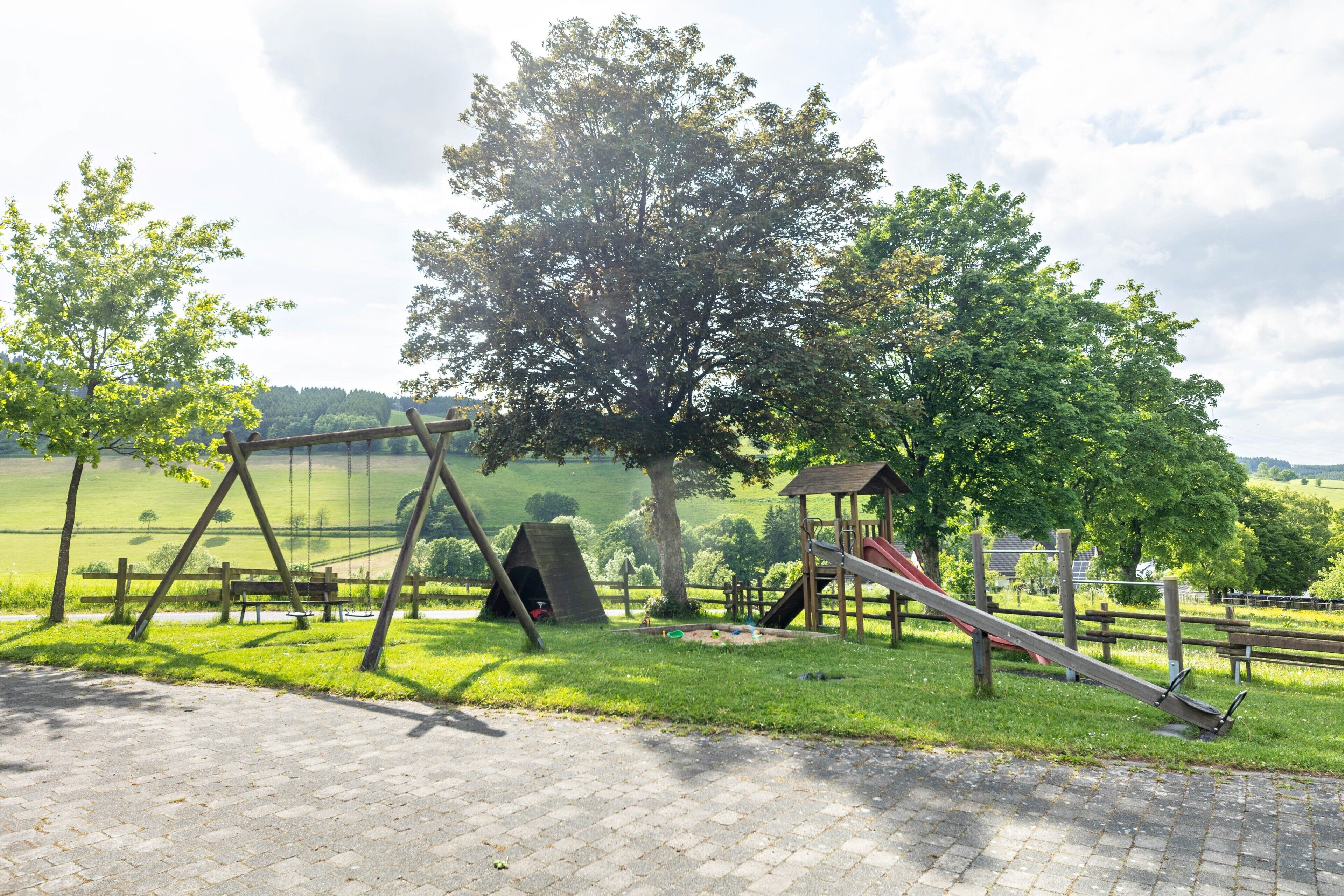 Ein Spielplatz mit Schaukeln, einer Rutsche und einer Kletterkonstruktion.