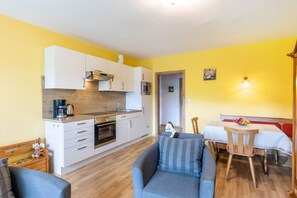 Un espace de vie compact comprenant un coin cuisine, un coin repas avec une table et des chaises, et un canapé.