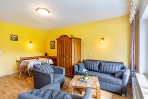 Un salon comprenant un ensemble de canapés, un meuble en bois et une table à manger avec des chaises.