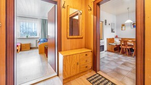 A wooden interior with a mirror, a wooden cabinet, a window with curtains, and a tiled floor. - Apartment 'Messe Hannover' with Shared Terrace, Shared Garden and Wi-Fi (Hannover)