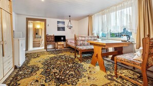 A room with a wooden ceiling, a patterned carpet, a dining table with chairs, a television, and a window with curtains. - Apartment 'Messe Hannover' with Shared Terrace, Shared Garden and Wi-Fi (Hannover)