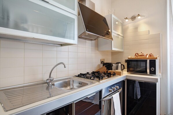 A modern kitchen with a gas stove, sink, microwave, and oven.