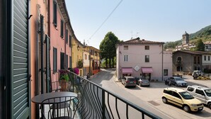 A street view with buildings, a balcony with a table and chairs, and parked cars.