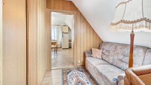A room with a sloped ceiling, wooden walls, a patterned sofa, a wooden floor, and a view through an open door. - Apartment 'Messe Hannover' with Shared Terrace, Shared Garden and Wi-Fi (Hannover)