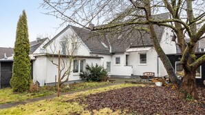 A residential house with a sloped roof, a pathway leading to the front door, and a yard with a pile of leaves. - Apartment 'Messe Hannover' with Shared Terrace, Shared Garden and Wi-Fi (Hannover)