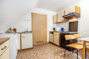 A compact kitchen with a stove, microwave, and wooden cabinets. - Apartment 'Messe Hannover' with Shared Terrace, Shared Garden and Wi-Fi (Hannover)