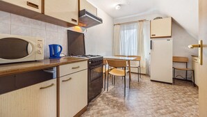 A compact kitchen with a microwave, stove, and cabinets. There is a dining table with chairs and a refrigerator. - Apartment 'Messe Hannover' with Shared Terrace, Shared Garden and Wi-Fi (Hannover)