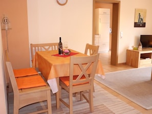 A dining area with a table set for two, a bottle of wine, and a vase with flowers.