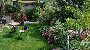Een tuin met een tafel en stoelen, omringd door verschillende planten en bloemen.