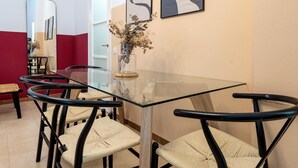 A dining area with a glass table, black chairs, and a vase with dried flowers. - Loft in the center 100 meters from the beach (Sant Feliu de Guíxols)