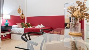 A room with a bed, a table, a lamp, and a decorative vase. - Loft in the center 100 meters from the beach (Sant Feliu de Guíxols)