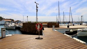 A wooden dock with a lifebuoy, boats, and a clear sky. - Loft in the center 100 meters from the beach (Sant Feliu de Guíxols)
