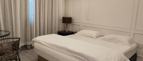 A hotel room with a bed, a nightstand, a lamp, a chair, and an air conditioning unit.