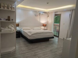 A modern bedroom with a large bed, a bedside table, a wardrobe, and a balcony with a glass door. - Lata Hotel (Nuku'alofa)