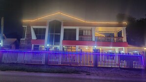 A hotel with a central entrance, a covered balcony, and a fenced front yard. - Lata Hotel (Nuku'alofa)