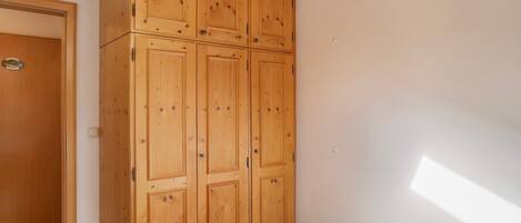 A bedroom with a wooden wardrobe, a bed with a patterned bedspread, and a sloped ceiling.