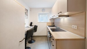 Una cocina compacta con horno integrado, un lavamanos y una ventana.