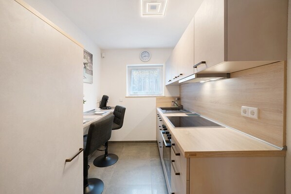 A compact kitchen with a built-in oven, a sink, and a window.