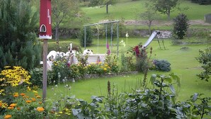 A garden with a birdhouse, a swing set, and a slide.