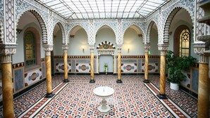 An interior with arches, a tiled floor, and a central fountain.