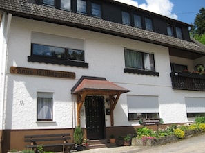 A building with a sign reading 'Haus Mühlgrund' and another sign for 'Fremdenzimmer Appartement.'