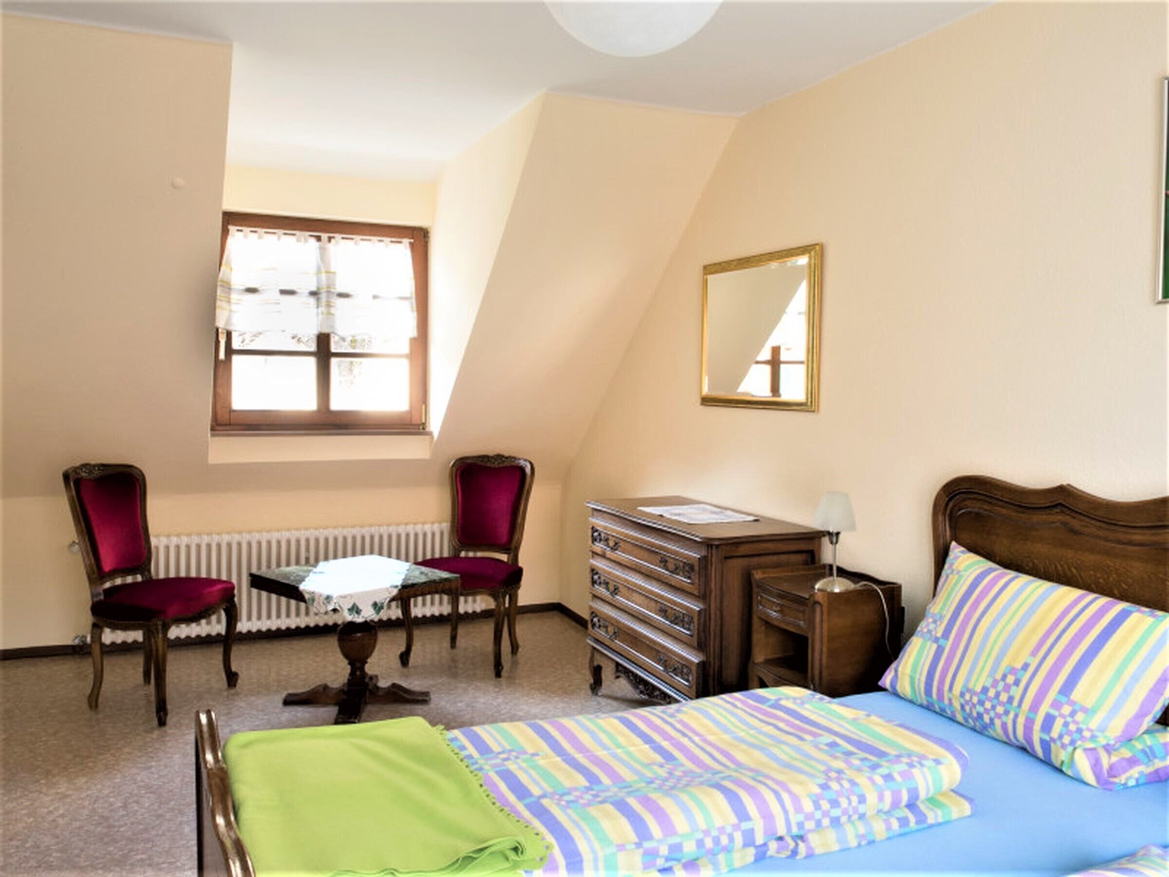Een slaapkamer met een bed, een kaptafel, een stoel, een tafel en een raam.