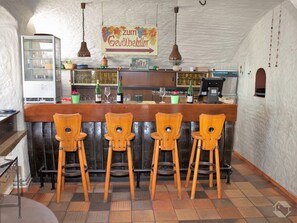 Un espace bar avec des chaises en bois, un comptoir avec des bouteilles et une enseigne au-dessus.