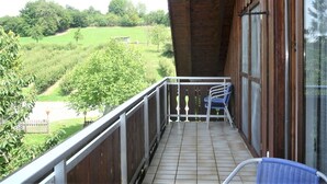 A balcony with a view of a green landscape, a metal railing, and a window with a view. - Apartment Obstgarten, 55 sqm, 2 bedrooms, max. 4 persons (Lindau)