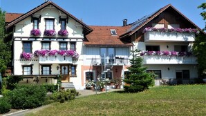 A two-story building with balconies, a staircase, and a small garden area. - Apartment Obstgarten, 55 sqm, 2 bedrooms, max. 4 persons (Lindau)