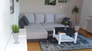 Un salon avec un canapé, une table basse, une petite table avec une plante et une plante en pot.