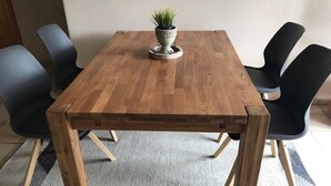 A wooden dining table with four chairs, a potted plant, and a rug. - Apartment 'Seeblick' with Shared Garden, Balcony and Wi-Fi (Lindau)