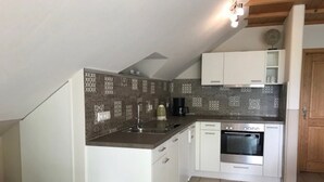 A compact kitchen with white cabinets, a built-in oven, and a tiled backsplash. - Apartment 'Seeblick' with Shared Garden, Balcony and Wi-Fi (Lindau)