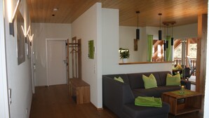 Una sala de estar moderna con un sofá, suelo de madera y un comedor con mesa y sillas.