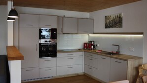 A modern kitchen with white cabinets, a built-in oven, a coffee maker, and a wooden countertop. - Apartment 'Hochtalblick' with Mountain View, Shared Garden and Wi-Fi (Ibach)