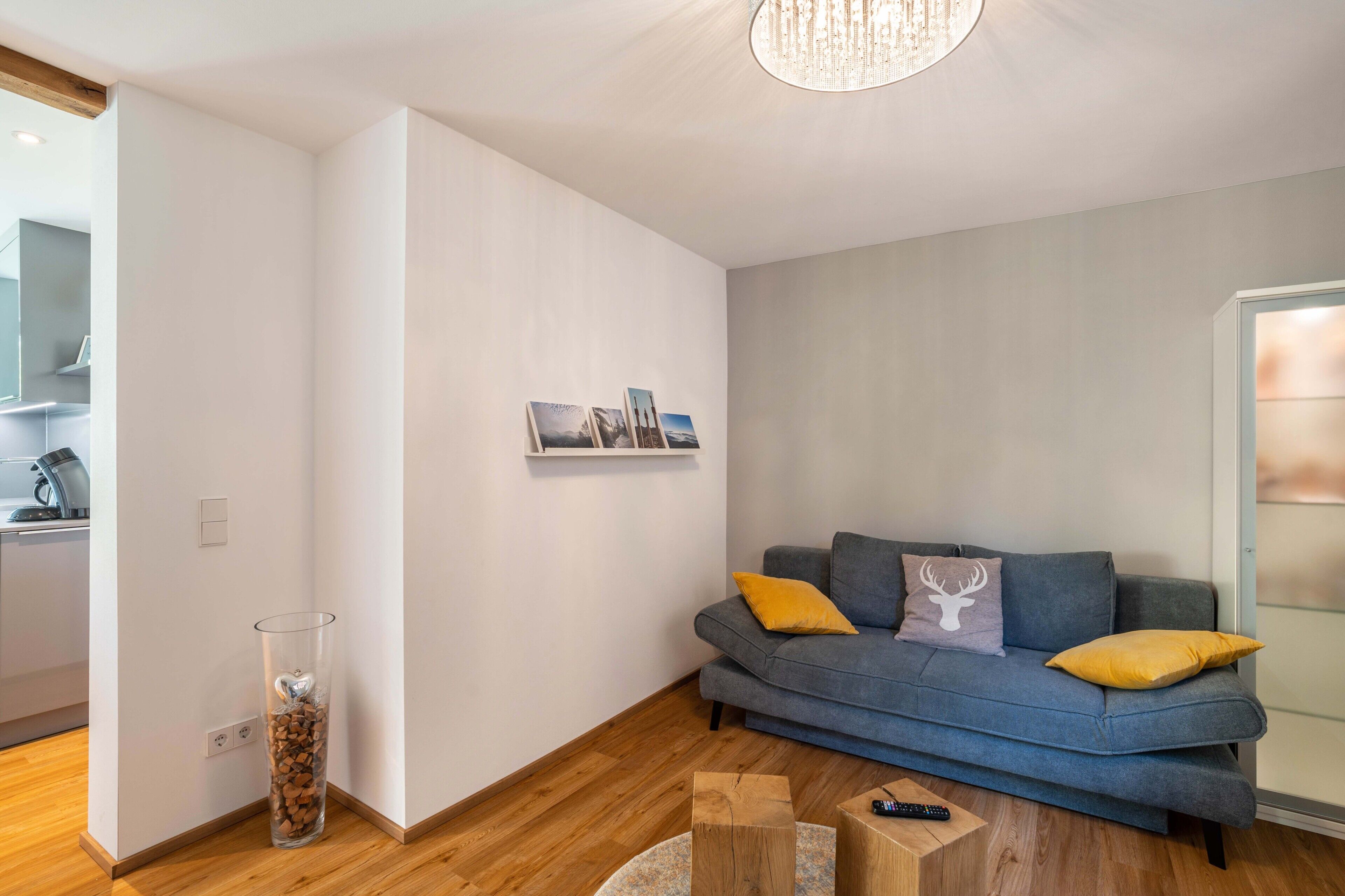 Een moderne woonkamer met een grijze bank, houten vloer en een glazen deur.