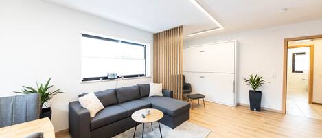 A modern living room with a sectional sofa, a small round table, and a potted plant.