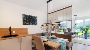 Ein moderner Essbereich mit Holztisch, Stühlen, einer Hängeleuchte und einem großen Fenster mit Aussicht.