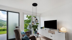 Ein stilvolles Wohnzimmer mit einer Couch, Fernseher und einer Topfpflanze.
