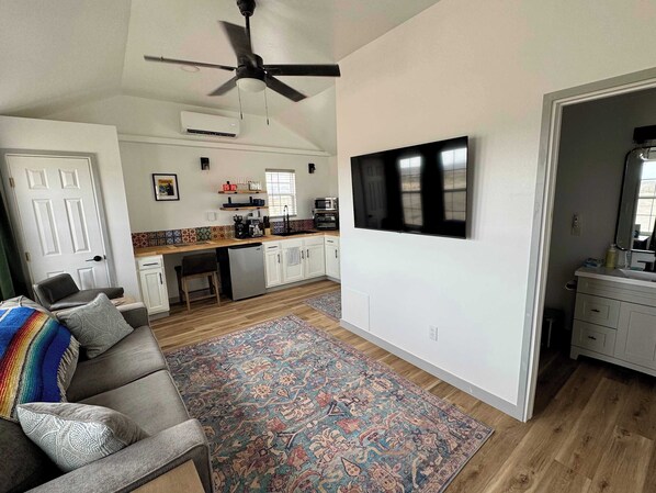 A modern living room with a grey sofa, a colorful rug, and a ceiling fan. - MJ's Cabin. Private cabin just 3.5 miles from BBNP (Terlingua)