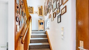 Eine Treppe mit hölzernen Geländern, eine Wand mit gerahmten Bildern und eine Tür mit Griff.