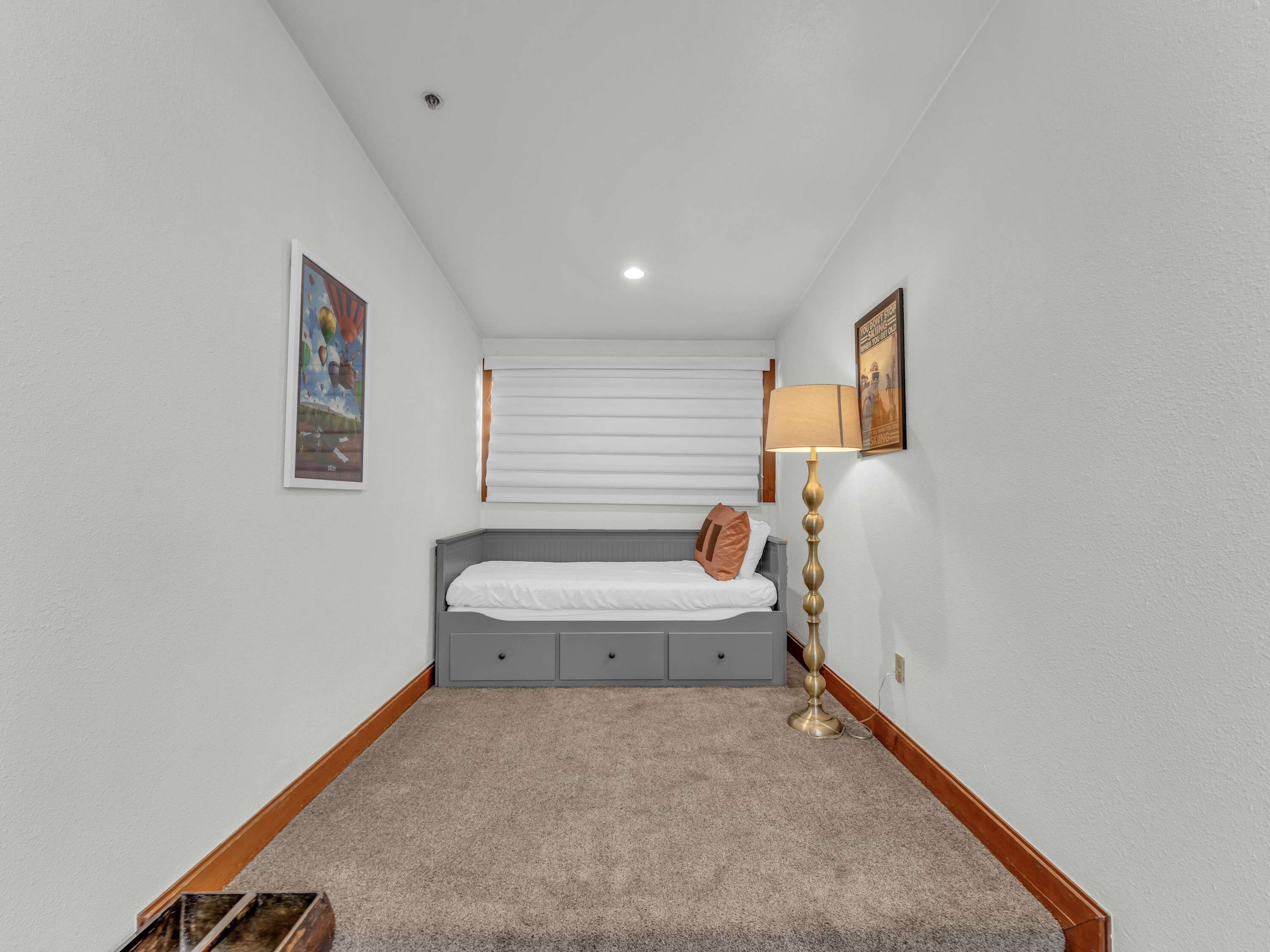 A bedroom with a bed, a lamp, and a painting on the wall.