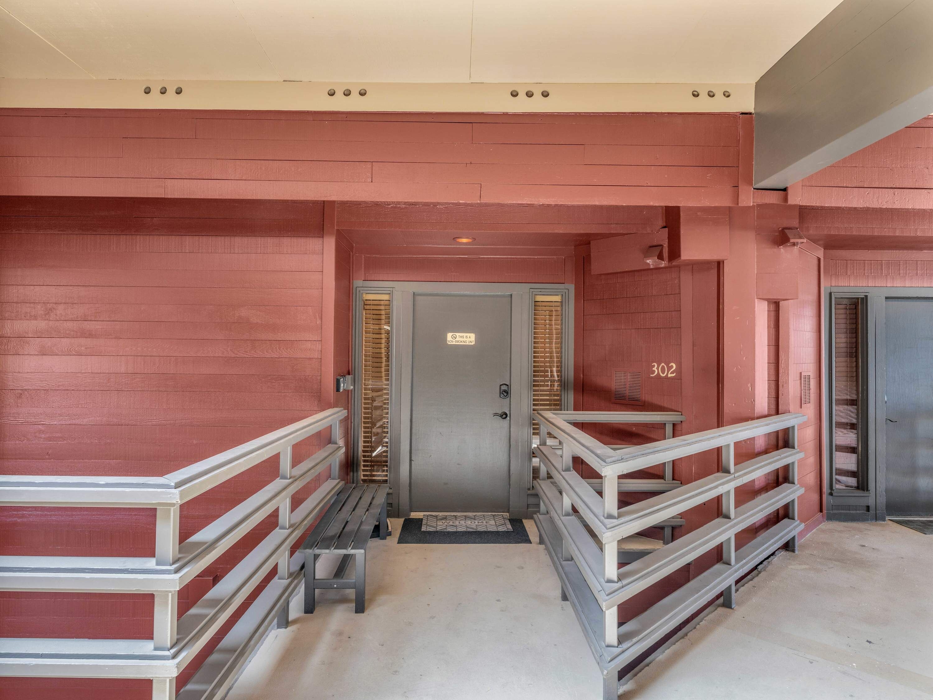 A hallway with a grey door marked "302" and a bench.