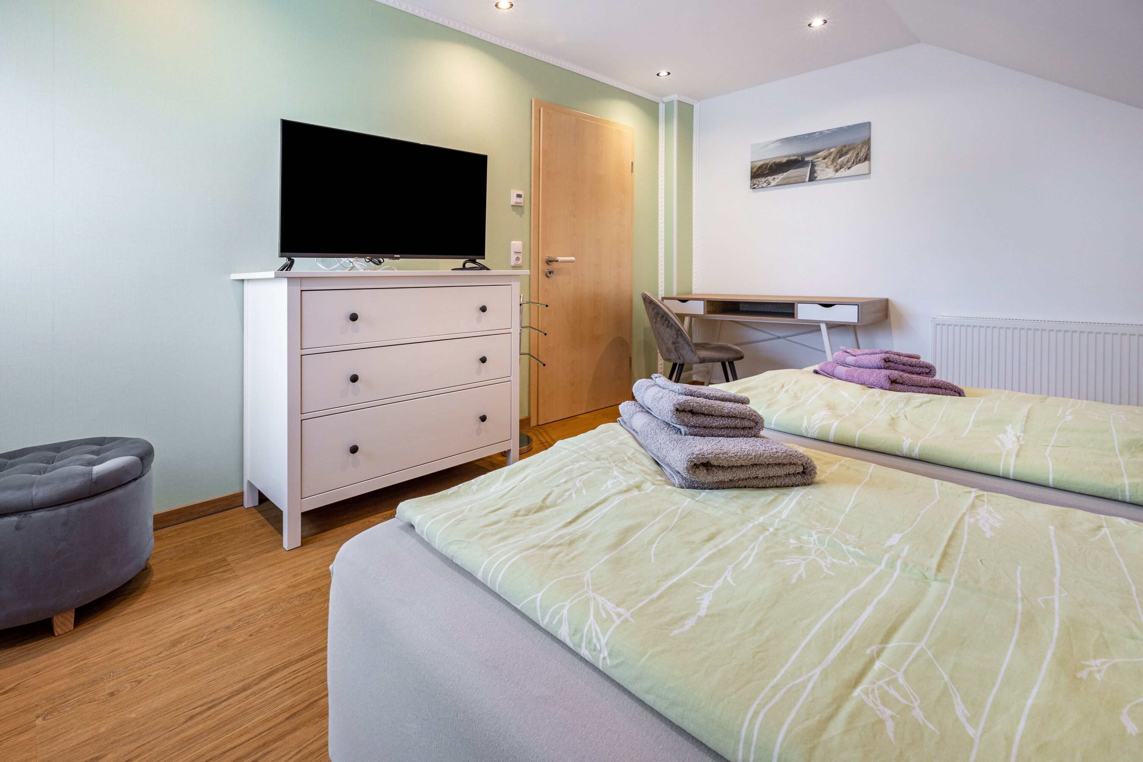 Ein Schlafzimmer mit zwei Betten, einem Fernseher, einem Schminktisch und einem Stuhl.