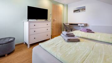 Ein Schlafzimmer mit zwei Betten, einem Fernseher, einem Schminktisch und einem Stuhl.