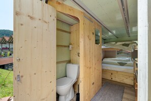 A compact, wooden interior with a toilet, a bed, and a small window. - Base Camp 'Poolhouse' with Private Pool and Black Forest Views (Bad Wildbad)