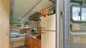 A compact kitchen with a refrigerator, wooden cabinets, and a window. - Base Camp 'Poolhouse' with Private Pool and Black Forest Views (Bad Wildbad)