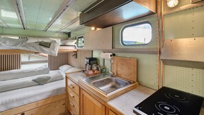 A compact RV interior with a bunk bed, kitchenette, and a small window. - Base Camp 'Poolhouse' with Private Pool and Black Forest Views (Bad Wildbad)