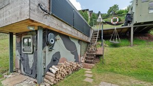 A rustic cabin with a wooden door, a staircase leading to a deck, and a hammock. - Base Camp 'Poolhouse' with Private Pool and Black Forest Views (Bad Wildbad)