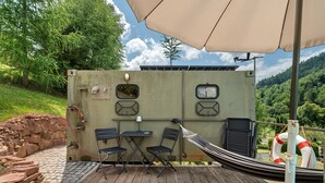 A deck with a table and chairs, a hammock, and a lifebuoy. - Base Camp 'Poolhouse' with Private Pool and Black Forest Views (Bad Wildbad)